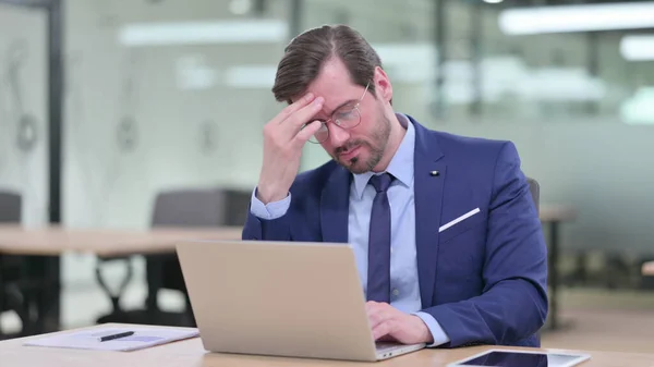 Gestresster junger Geschäftsmann mit Laptop hat Kopfschmerzen im Büro — Stockfoto