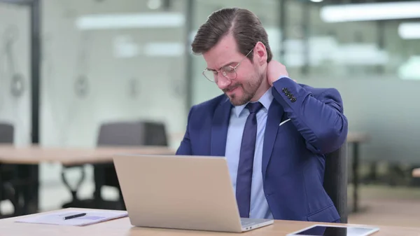 Moe van jonge zakenman met laptop met nekpijn in kantoor — Stockfoto
