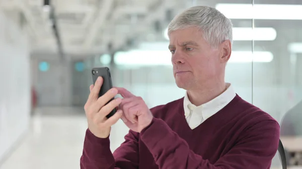 Среднего возраста бизнесмен просматривает Интернет на смартфоне — стоковое фото