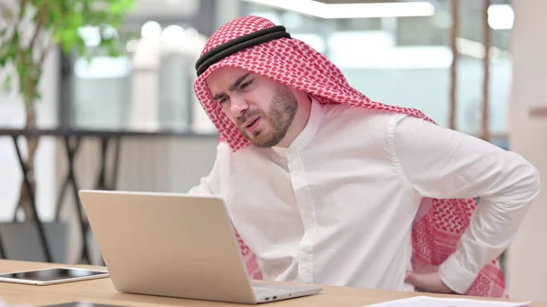Κουρασμένος Άραβας επιχειρηματίας με φορητό υπολογιστή που έχει πόνο στην πλάτη στο γραφείο — Φωτογραφία Αρχείου