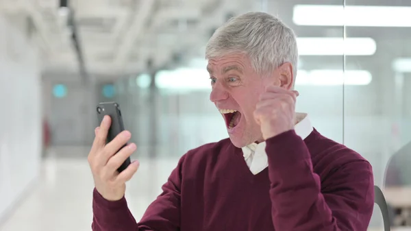 Geschäftsmann mittleren Alters feiert auf dem Smartphone — Stockfoto