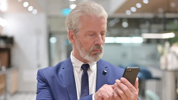 Portrait de vieil homme d'affaires concentré naviguant sur Internet sur Smartphone — Photo