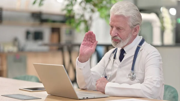 Médico velho fazendo chamada de vídeo no laptop no escritório — Fotografia de Stock