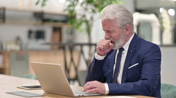 Zieke oude zakenman met laptop hoesten in kantoor — Stockfoto