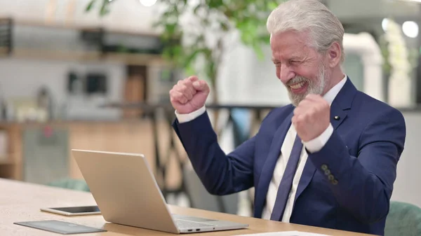 Vieil homme d'affaires célébrant le succès sur ordinateur portable au bureau — Photo