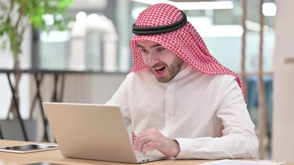 Joyeux homme d'affaires arabe célébrant le succès sur ordinateur portable au bureau — Photo