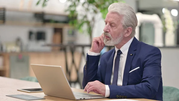 Vieux homme d'affaires Penser et travailler sur ordinateur portable dans le bureau — Photo