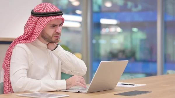 Zestresowany arabski biznesmen z laptopem mając ból szyi w biurze — Zdjęcie stockowe