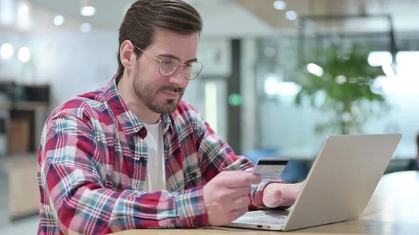 Молодой человек делает онлайн покупки на ноутбуке в кафе — стоковое фото