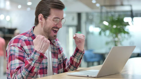 Jovem animado comemorando o sucesso no laptop no café — Fotografia de Stock