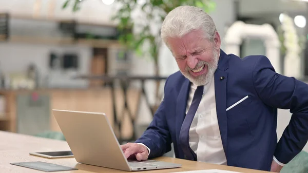 オフィスで背中の痛みを持つノートパソコンを持つ古いビジネスマン — ストック写真