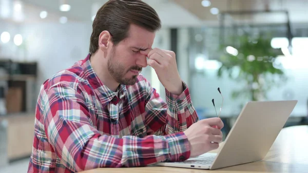 Gestresster junger Mann mit Laptop hat Kopfschmerzen im Café — Stockfoto