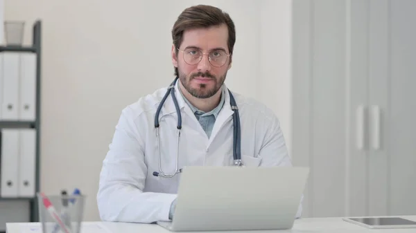 Doctor joven con portátil mirando a la cámara — Foto de Stock