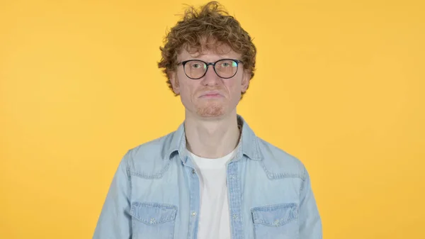 Vastenmielinen punapää nuori mies reagoi keltaisella taustalla — kuvapankkivalokuva
