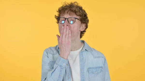 Zívající zrzavý mladý muž na žlutém pozadí — Stock fotografie