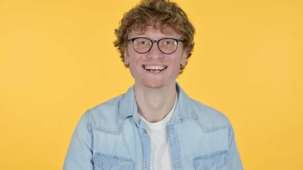 Punapää nuori mies nauraa vitsi keltaisella taustalla — kuvapankkivalokuva