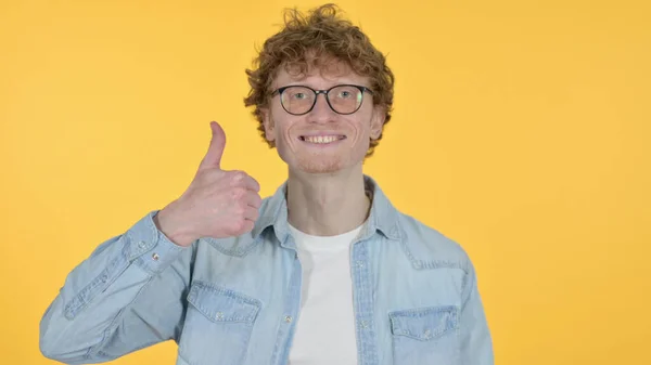 Jeune homme rousse avec pouce vers le haut sur fond jaune — Photo