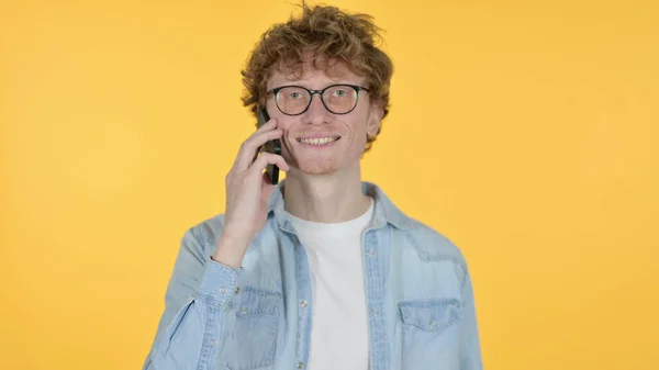 Zrzka Mladý muž mluví na telefonu na žlutém pozadí — Stock fotografie
