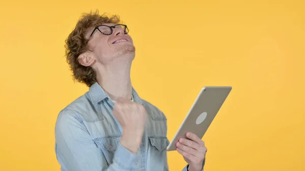 Rotschopfjunger Mann feiert auf Tablet auf gelbem Hintergrund — Stockfoto