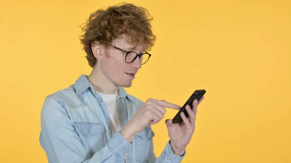 Ruiva jovem homem usando Smartphone em fundo amarelo — Fotografia de Stock