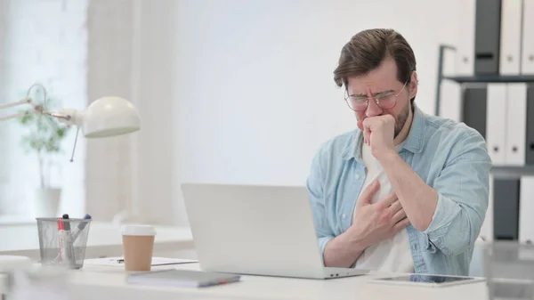 Junger Mann mit Laptop hustet bei der Arbeit — Stockfoto