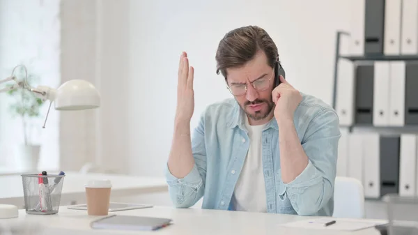 Wütender junger Mann telefoniert bei der Arbeit — Stockfoto