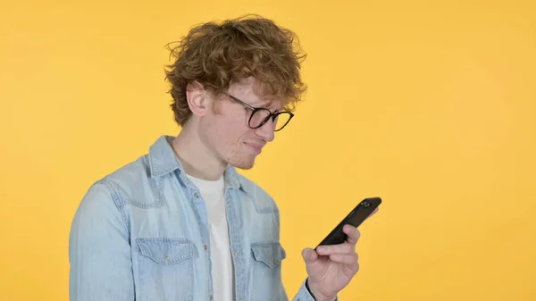 Redhead Joven Pérdida en Smartphone sobre fondo amarillo —  Fotos de Stock