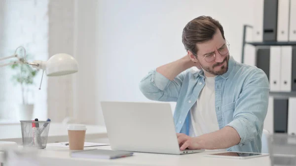 Junger Mann mit Nackenschmerzen arbeitet am Laptop — Stockfoto