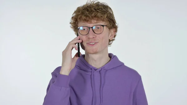 Рыжий молодой человек разговаривает по телефону на белом фоне — стоковое фото