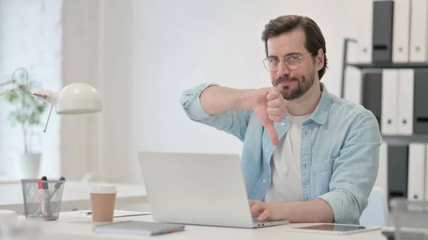 Pouces vers le bas par jeune homme avec ordinateur portable au travail — Photo