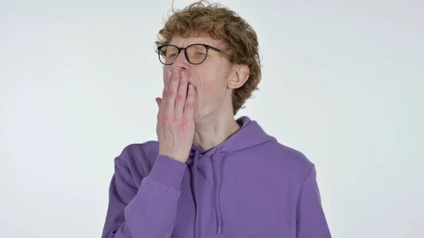 Yawning rödhårig ung man på vit bakgrund — Stockfoto