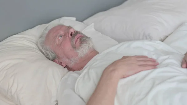 Töprengő öregember feküdt az ágyban gondolkodás — Stock Fotó