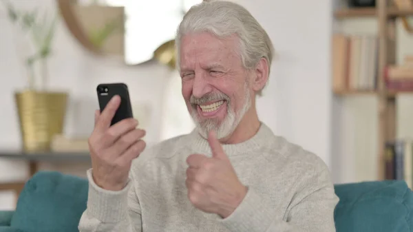 Älterer Mann feiert zu Hause mit Smartphone — Stockfoto