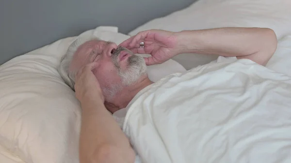 Starszy starzec z bólem głowy w łóżku — Zdjęcie stockowe