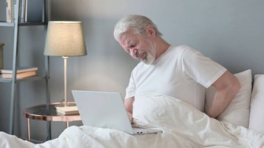 Dizüstü bilgisayarı olan yaşlı bunağın yatağında sırt ağrısı var.