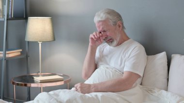 Yatakta oturup ağlayan yaşlı bunak.