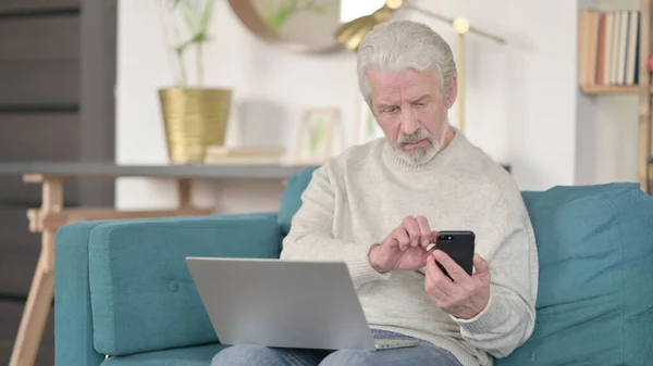 Senior Old Man working on Smartphone and Laptop at Home