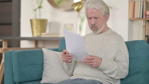 Napięty starszy człowiek czytanie dokumentów w domu — Zdjęcie stockowe
