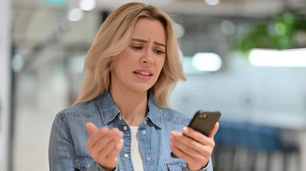 Retrato de la joven mujer casual reaccionando al fracaso en el teléfono inteligente —  Fotos de Stock