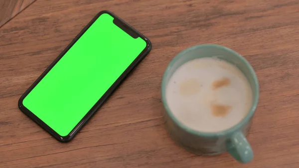 Smartphone con schermo cromato sul tavolo accanto al caffè — Foto Stock