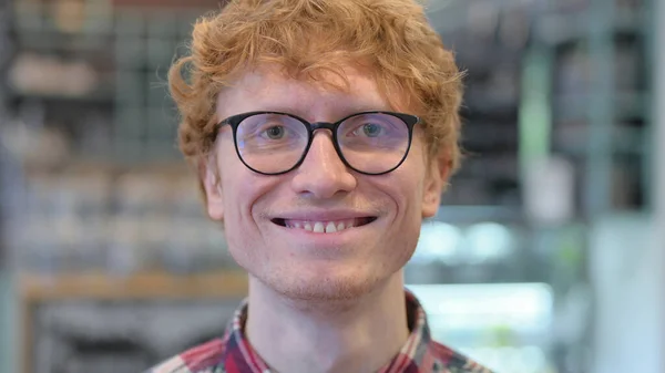 Närbild, rödhårig ung man ler mot kameran — Stockfoto