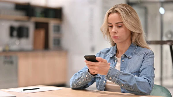 Junge Gelegenheitsfrau nutzt Smartphone bei der Arbeit — Stockfoto