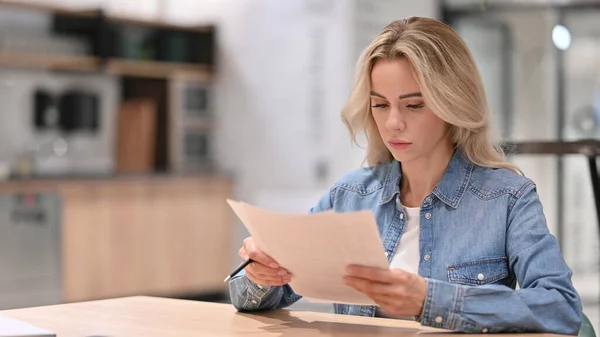 Jeune femme occasionnelle lisant des documents au travail — Photo