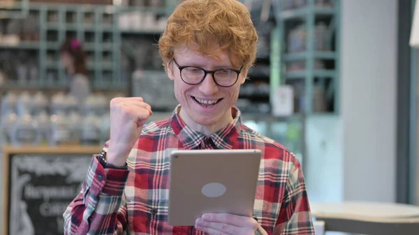 Portrait de jeune homme rousse excité célébrant le succès sur tablette — Photo