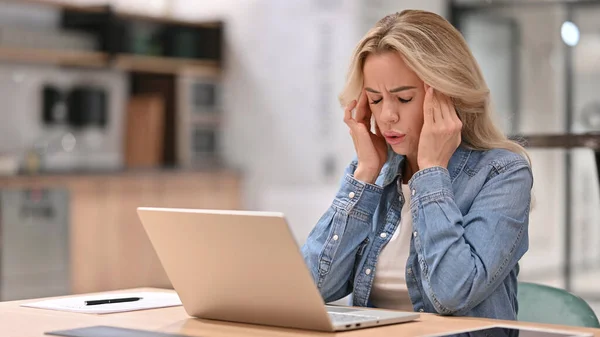 Junge Gelegenheitsarbeiterin mit Kopfschmerzen nutzt Laptop bei der Arbeit — Stockfoto