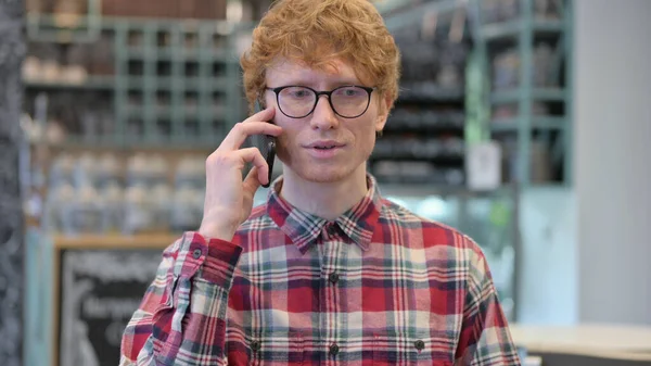 Porträtt av ung rödhårig ung man talar i telefon — Stockfoto