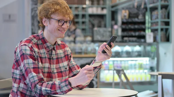El éxito de compras en línea de pago en Smartphone por Redhead Young Man —  Fotos de Stock