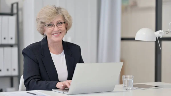 Alte Geschäftsfrau mit Laptop lächelt in die Kamera — Stockfoto