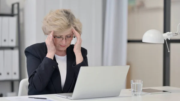 Vieille femme d'affaires ayant mal à la tête tout en travaillant sur ordinateur portable — Photo