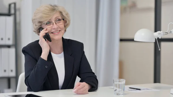 Alte Geschäftsfrau telefoniert bei der Arbeit — Stockfoto